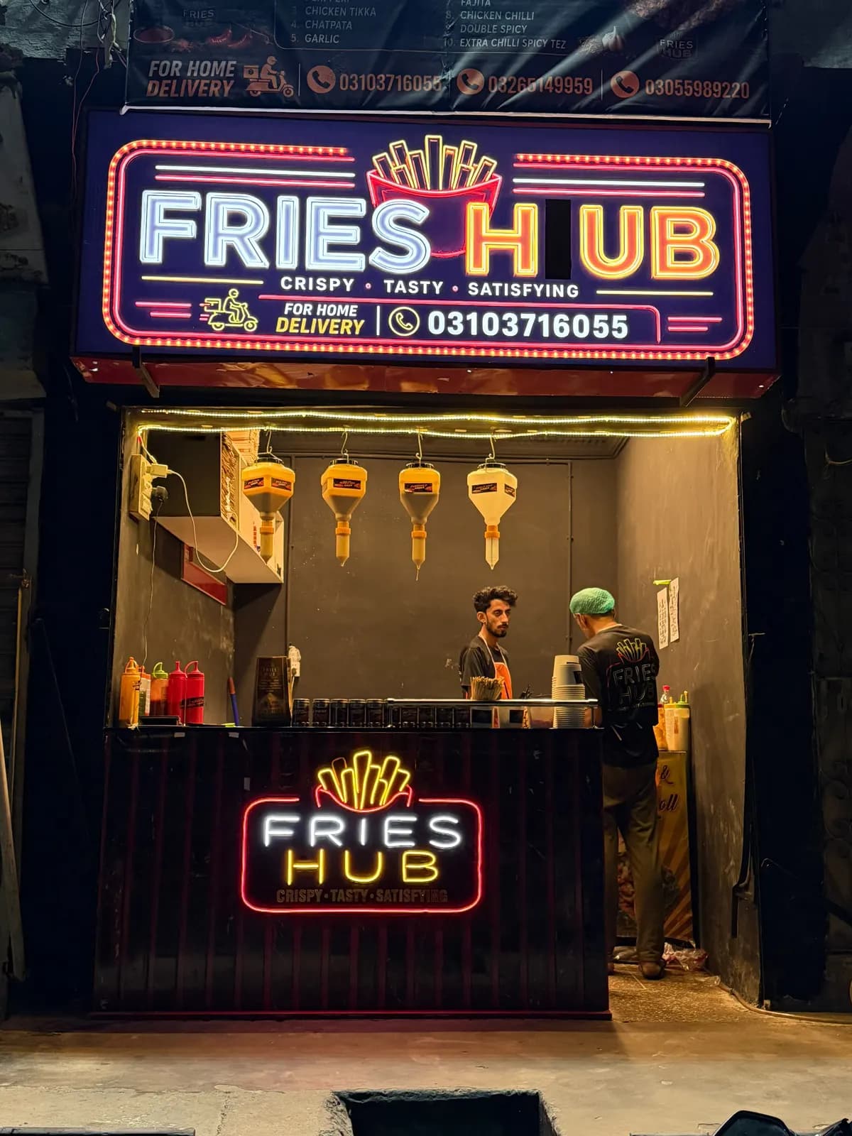 The Fries Hub shop front at night with its neon sign